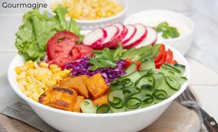 Eine weisse Schüssel gefüllt mit Süsskartoffeln, verschiedenen Gemüsen und Salaten