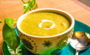 Eine verzierte Schüssel gefüllt mit Brokkoli-Crème-Suppe auf einem blaugrünen Teller