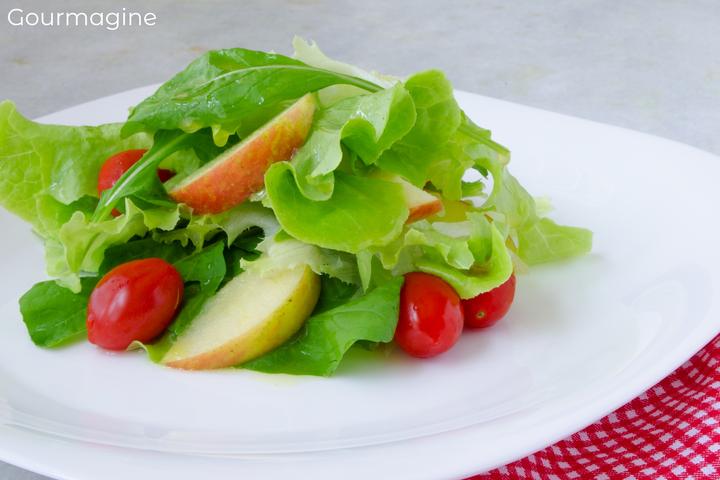 Lettuce, rocket, cherry tomatoes and apple pieces on a white plate