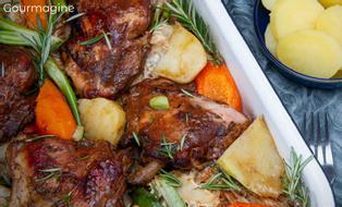 Baked chicken pieces, potatoes, carrots and rosemary served on a bed of cabbage in an oven dish