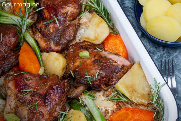 Baked chicken pieces, potatoes, carrots and rosemary served on a bed of cabbage in an oven dish