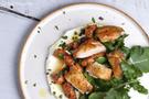 Chicken pieces, carrots and rocket on a bed of yoghurt on a white plate