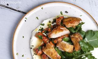 Chicken pieces, carrots and rocket on a bed of yoghurt on a white plate