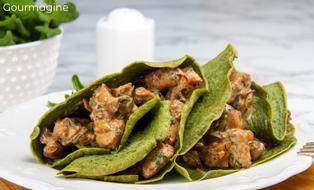 Two green spinach crêpes filled with a chicken mixture served on a white plate