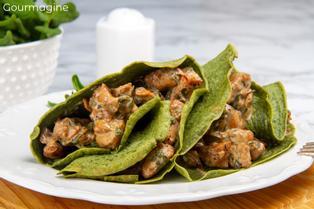 Two green spinach crêpes filled with a chicken mixture served on a white plate