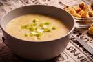 A dark brown bowl filled with potato leek soup