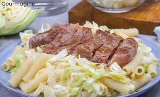 A sliced, fried steak served on a plate with macaroni and cabbage
