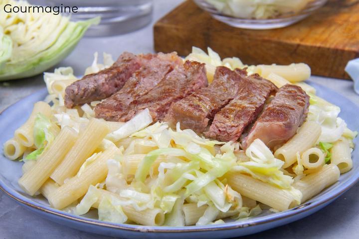 Ein geschnittenes, gebratenes Steak angerichtet auf einem Teller mit Makkaroni und Kabis