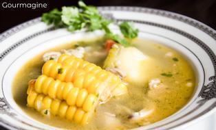 Eine weisse Schüssel gefüllt mit klarer Poulet-Suppe und Maiskolben