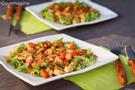 Zwei viereckige Teller mit gebratenem Poulet, Peperonistücken und grünen Salatblättern