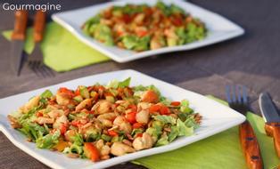 Two square plates with fried chicken, pieces of pepperoni and green salad leaves