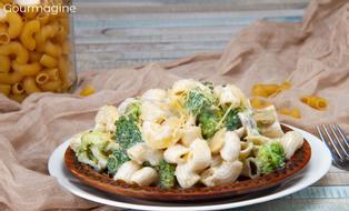 A brown plate filled with elbow pasta, broccoli and mushrooms with cheese sprinkled on top