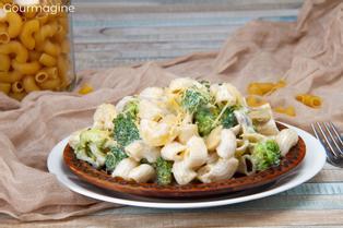 A brown plate filled with elbow pasta, broccoli and mushrooms with cheese sprinkled on top