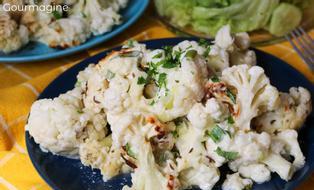 Pieces of cauliflower baked with cheese, onions and parsley on a blue plate