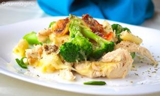 Baked penne, broccoli, chicken and cheese served on a white plate