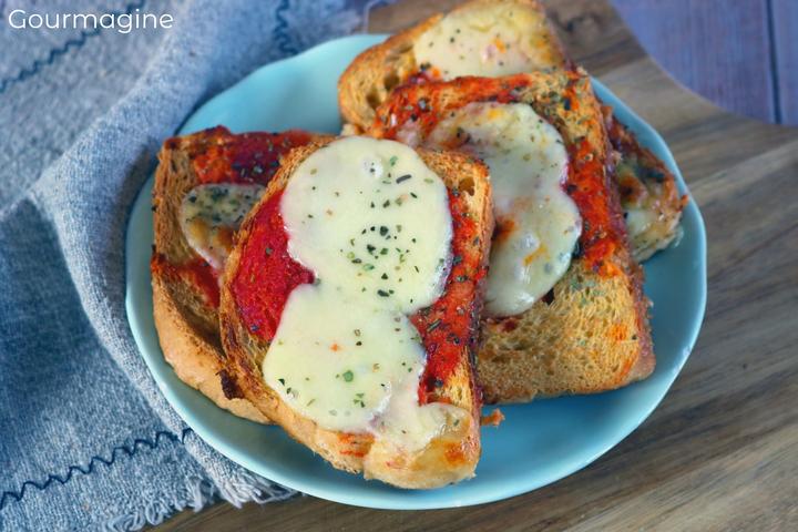 A light blue plate with baked stale bread slices covered with tomato sauce and mozzarella