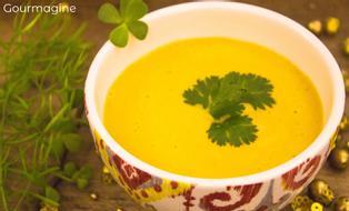 A decorated bowl filled with yellow carrot soup