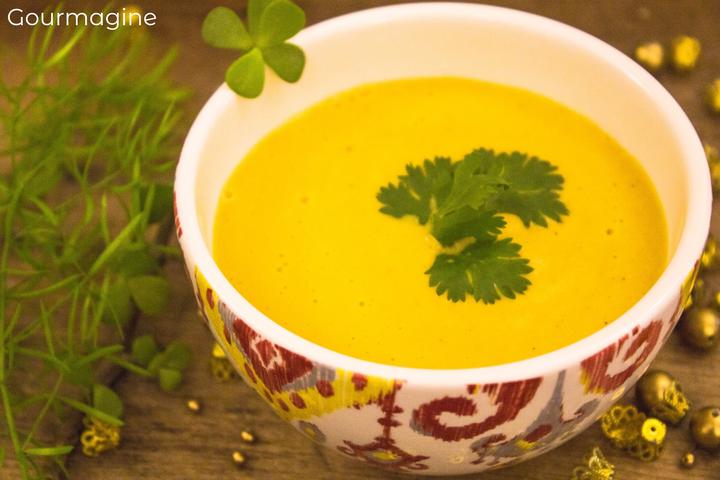 A decorated bowl filled with yellow carrot soup