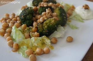 Brokkolistücke, Kichererbsen und Salatblätter angerichtet auf einem weissen Teller