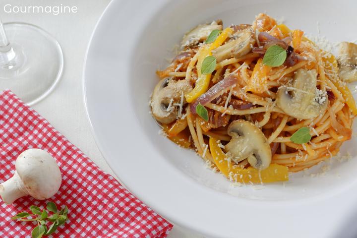 Spaghetti, mushrooms, onions and tomato sauce served on a white plate