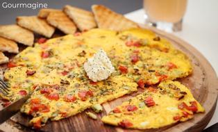An omelette with pepperoni, courgettes and feta on a wooden plate