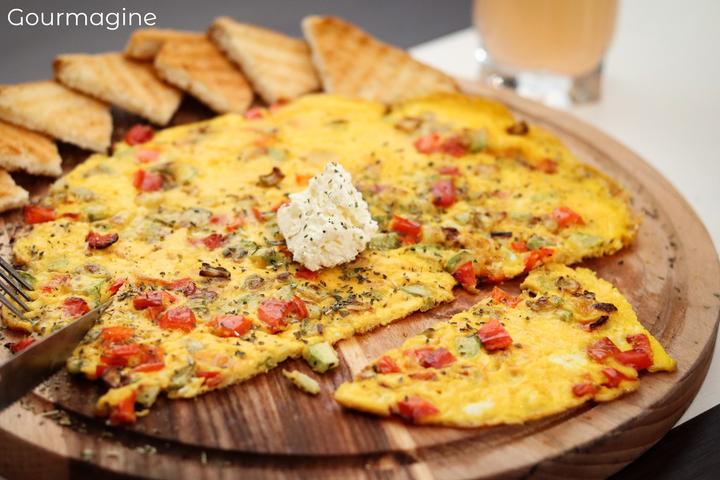 An omelette with pepperoni, courgettes and feta on a wooden plate