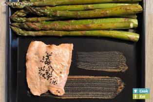 Salmon with sesame and green asparagus on a black baking tray