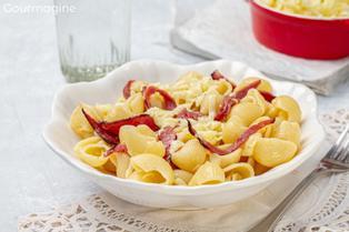 A white plate filled with elbow pasta, strips of fried cured beef and grated Appenzell cheese