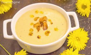 A cauliflower chickpea soup served in a white pot and decorated with yellow flowers