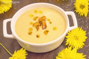 A cauliflower chickpea soup served in a white pot and decorated with yellow flowers