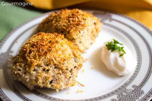 Two pieces of chicken with a cheese and basil crust served on a white plate
