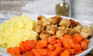 Gedämpfte Rüebli, gebratene Pouletstücke und Kartoffelstock angerichtet auf einem weissen Teller