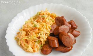 Cabbage carrot salad and a sliced Vienna sausage served on a white plate