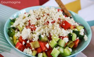Eine grüne Schüssel gefüllt mit Gurken, Tomaten, Peperoni und Käse