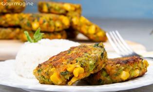 Two brown vegetable patties of broccoli, corn and spinach served on a white plate with white rice