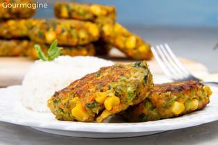 Two brown vegetable patties of broccoli, corn and spinach served on a white plate with white rice