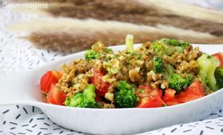 A white bowl filled with a salad of broccoli, tomatoes and walnuts