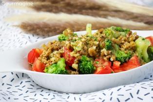 A white bowl filled with a salad of broccoli, tomatoes and walnuts