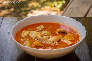 Weisse Schüssel gefüllt mit authentischem thailändischem Massaman-Curry mit Poulet und Kartoffeln auf einem Holztisch im Dschungel
