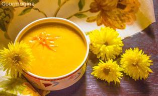 A bowl filled with lentil soup next to yellow flowers