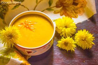 A bowl filled with lentil soup next to yellow flowers